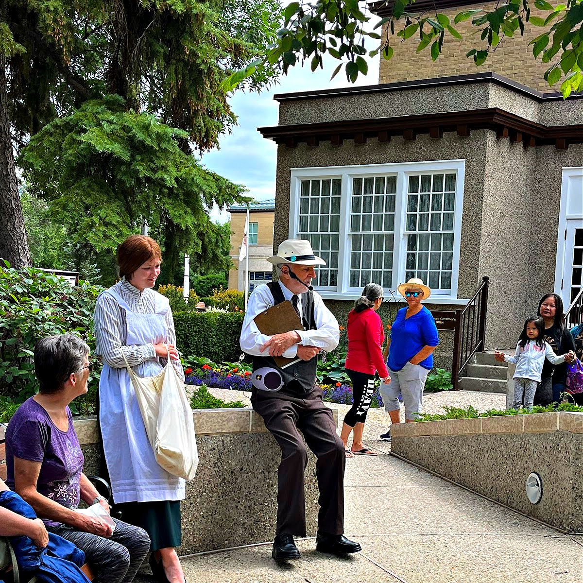 Young lady and gentleman dressed in Victorian costume doing a tour in the gardens
