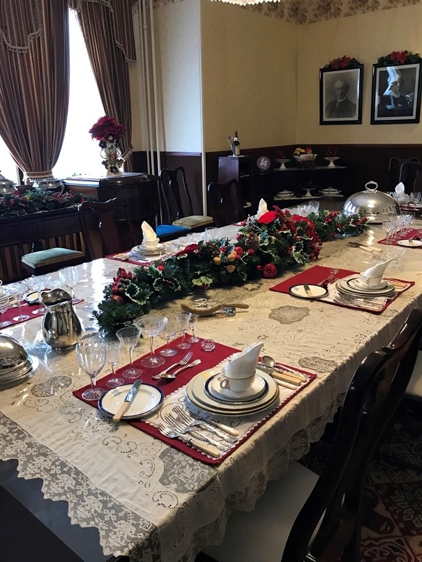 A wooden dining room table that is set for dining located in the dining room of the museum in Government House SK