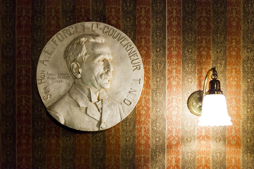 A white medallion of A. E. Forget hanging on the wall in the ceremonial entrance of the museum in Government House SK