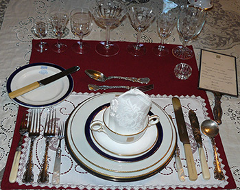 A place setting on a dining room table that is made up of the original china, crystal and silverware of Government House SK