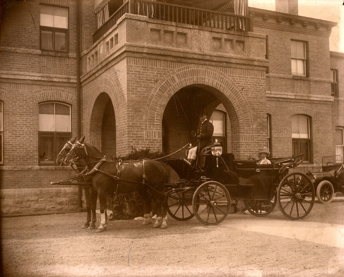 The Provincial Landau outside Government House hooked up to two horse and a driver and a lady sitting in it