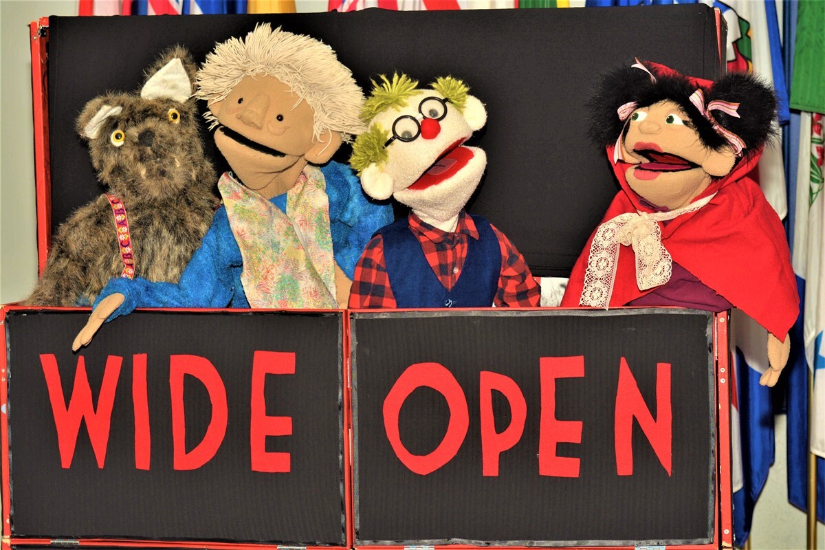 A wolf, two male and one female puppet in a puppet stage-booth.