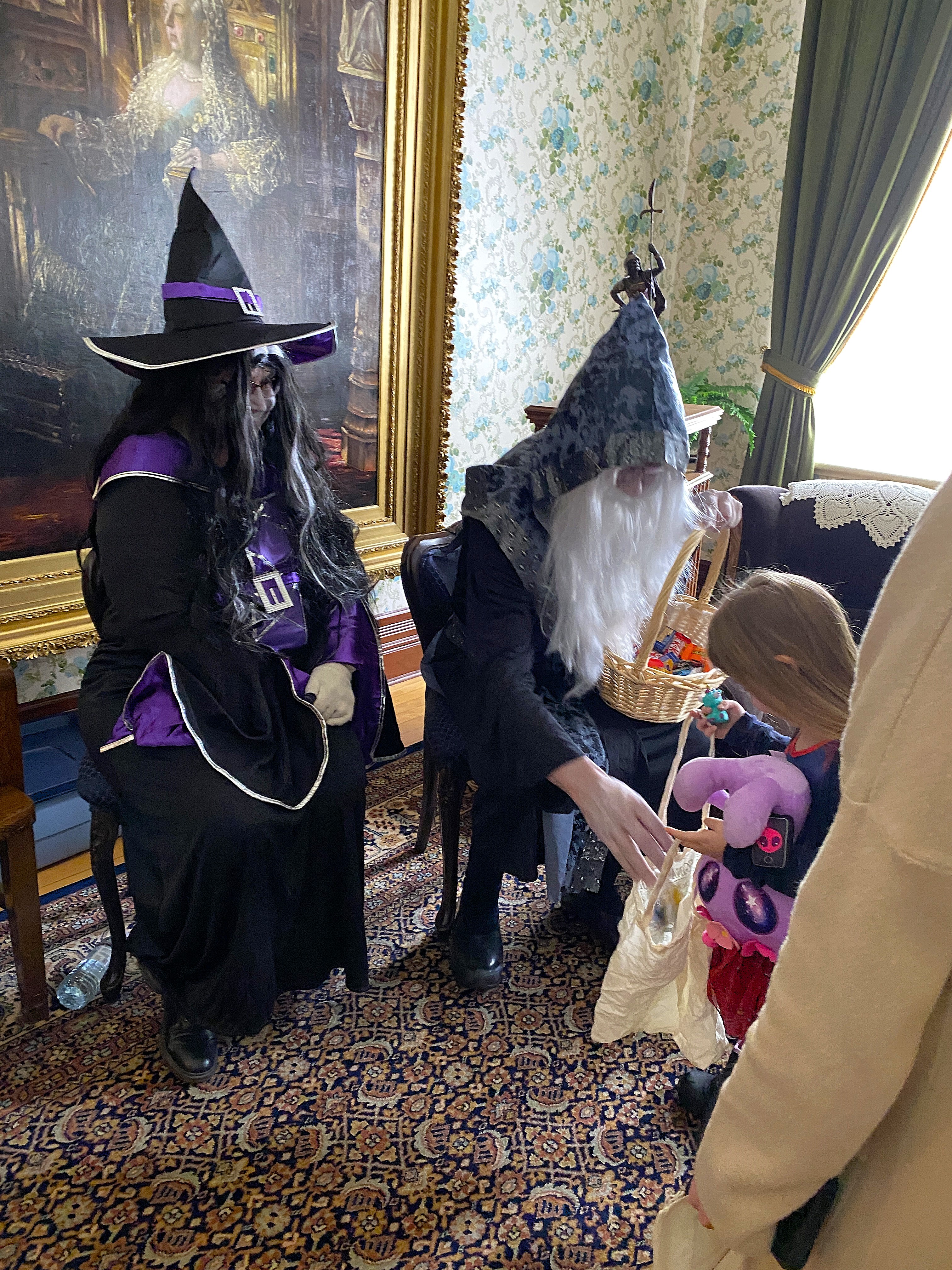 Two people dressed in Halloween Costumes handing out candy in a room.