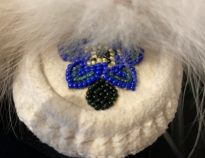 Close up of a white moccasin with multi-colooured beading and white fur
